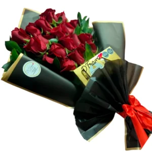 Ramo grande de rosas rojas en papel negro mate con bordes dorados y caja de bombones Ferrero Rocher.